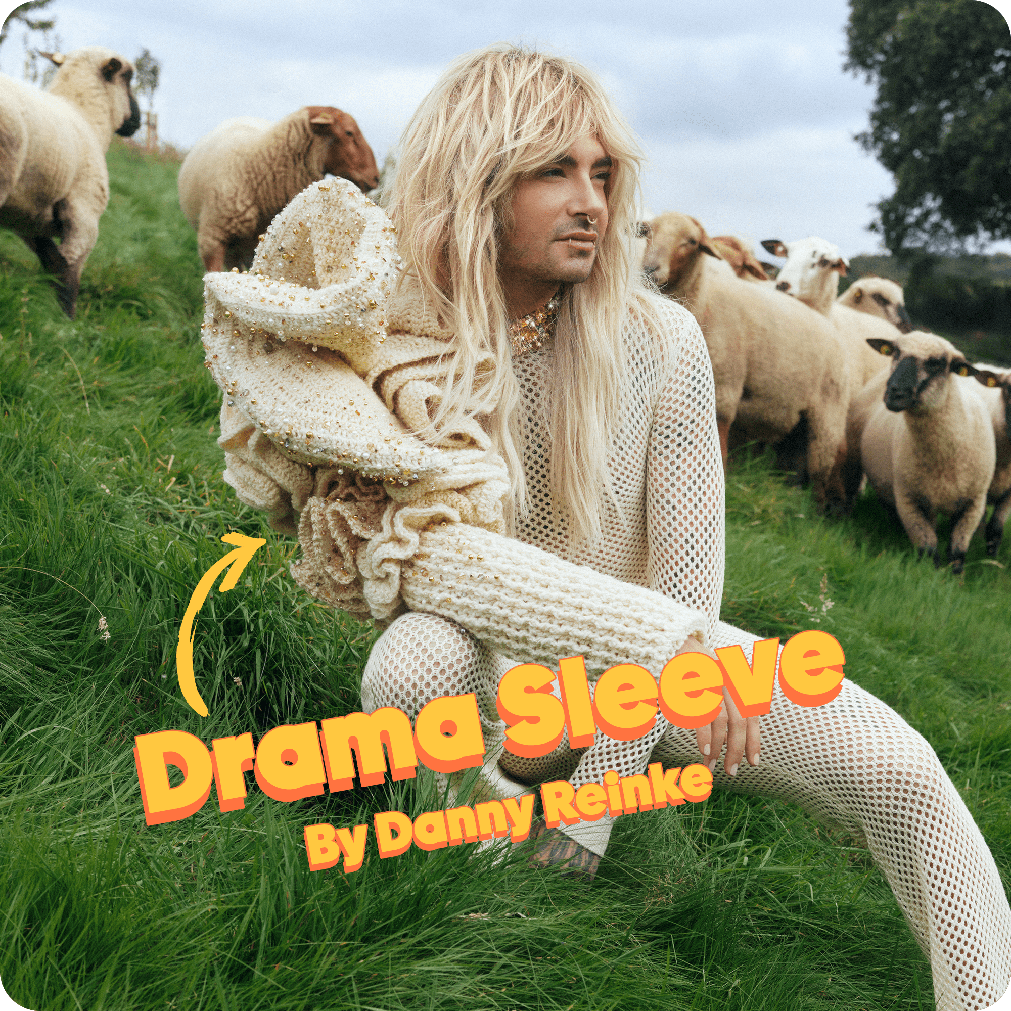 Bill Kaulitz posing at Rainbowwool Farm, wearing the Drama-Sleeve, with  sheep grazing in the background.